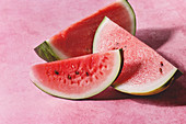 Ripe sliced watermelon over pink texture background