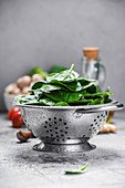 Fresh organic spinach leaves in metal colander and healthy ingredients