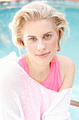 A blonde woman wearing a pink top and a white summer jumper