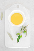 Olivenöl im Schälchen auf Schneidebrett mit Etikett