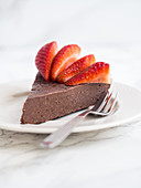 Slice of a flourless chocolate fudge cake with strawberries (vegan and paleo)