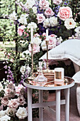 Candles and glass carafe on round side table in front of roses