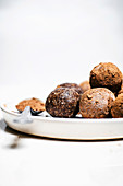 Chocolate hazelnut energy bites rolled in cocoa with white background.