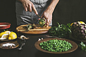 A man prepares lunch with artichokes and peas