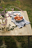 Schale mit Eiern auf einem Tuch auf dem Tisch im Garten