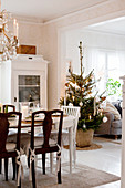 Festively decorated dining table, glass-fronted cabinet and decorated Christmas tree in Scandinavian dining room