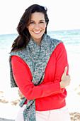 A brunette woman wearing a red jumper with a grey-flecked jumper over her shoulders