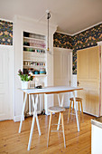 High table and bar stools in front of shelves of crockery in kitchen with wooden floor