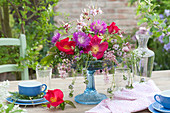 Frühsommer-Gesteck mit Rose 'Scharlachglut', Flockenblume, Flieder und Storchsch