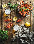 Two pints of wheat beer and boiled crayfish with lemon and parsley over old wooden rustic background