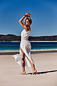 A young woman on the beach wearing a white dress