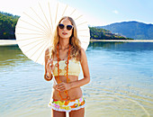 Junge Frau mit Sonnenschirm im Bikini am Strand