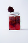 A glass of plum jam against a white background