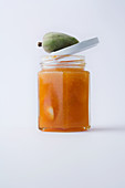 A glass of almond jam against a white background