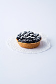 A mini tartlet with blueberries against a white background