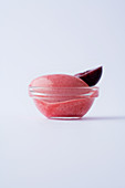 Cherry sorbet in a glass bowl against a white background