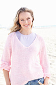 Blonde Frau in lila T-Shirt und rosa Pullover