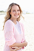 A blonde woman wearing a purple t-shirt and a pink jumper