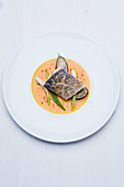 Sea bass fillet with lemon grass and ginger flowers, roasted aubergines and spicy pumpkin sauce