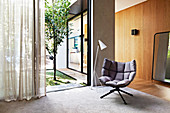 Gray designer armchair and floor lamp in front of patio door