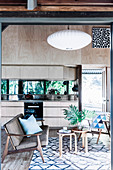 Open kitchen with light wooden front and mirrored back wall, seating area in the foreground