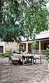 Rustikal gedeckter Gartentisch im sommerlichen Innenhof