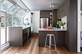 Elegant, dark fitted kitchen with breakfast bar, stainless steel fridge and window front