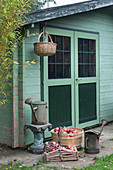 Baskets of pomegranates and watering cans outside summerhouse