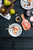 A slice of bread with marmelade, a cup of tea, pears from above on a black wooden table