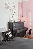 Piano against pink wall and panelled door in bedroom