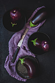 Eggplants on dark plates and purple linen tea towel