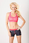 Junge blonde Frau in pinkfarbenem Sport-BH und Shorts