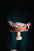 A woman holding an apple pie on a cake stand