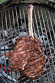 Tomahawk-Steak vom Kalb auf Grillrost über Grillfeuer (Aufsicht)