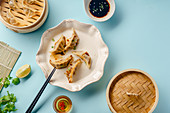 Fried Gyoza dumplings with duck cooked in bamboo steamer served with soy sauce, sesame seeds and cilantro