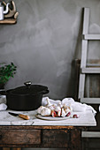 Kochtopf und Knoblauch auf rustikalem Küchentisch