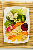 A vegan vegetable platter on a straw mat