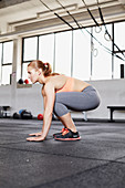 A young woman performing a burpee