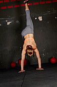 A young woman performing a wall handstand