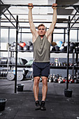 A young man performing a strict pull-up on a pull-up bar