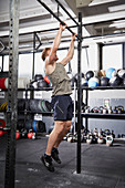 A young man performing a burpee pull-up on a pull-up bar