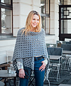 A blonde woman wearing a hand-crocheted poncho shawl