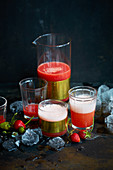 Strawberry drink in a carafe and glasses against a black background