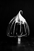 Meringue on a whisk on a black surface