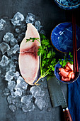 Schwertfischsteak auf Eis daneben Korinader, Messer und asiatische Schälchen