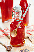 Red chili jam in a bottle with a wooden spoon for gifting