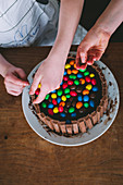 Children hands decorating a cake with colored candy