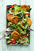 A colourful salad with falafel rounds and tahini sauce