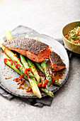 Salmon in a chia crust on green asparagus with chili