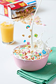 Milk being poured into a bowl of colourful cereal